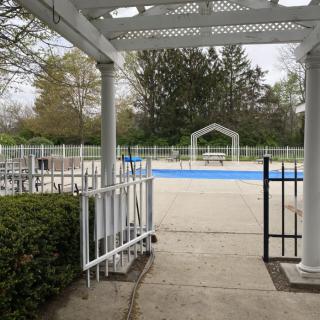 An empty outdoor pool area surrounded by trees and a gazebo.