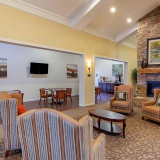 A cozy living room with a fireplace, comfortable seating, and a television on the wall.
