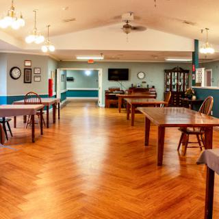 A spacious community room featuring wooden tables and a warm ambiance.