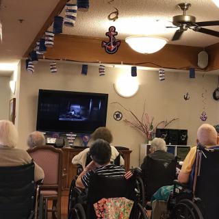 A group of elderly individuals watching television together in a nursing home.
