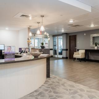 A modern reception area featuring a curved desk, contemporary lighting fixtures, and comfortable seating in a neutral color palette.