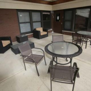 An outdoor patio area with chairs and a table in front of a building.