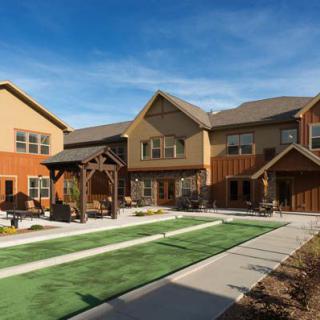 A modern residential building with a landscaped yard and clear blue skies.