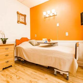 A cozy hospital room with an orange accent wall and a single bed.