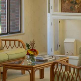 A cozy living room with a wicker sofa, wooden coffee table, and a vase of flowers.