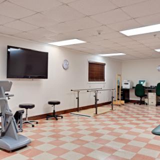A well-equipped physical therapy room featuring exercise machines and rehabilitation bars.