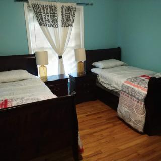 A cozy bedroom with twin beds, a nightstand, and decorative curtains.