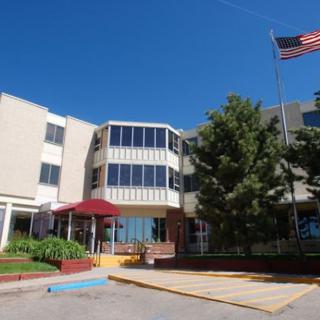 Exterior view of a building with an American flag and surrounding trees.