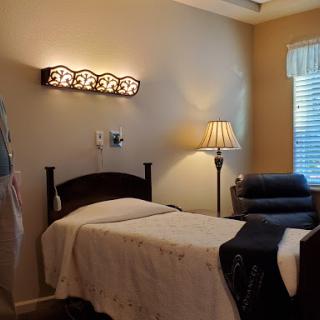A cozy and well-lit bedroom featuring a neatly made bed, a comfortable chair, and warm lighting.