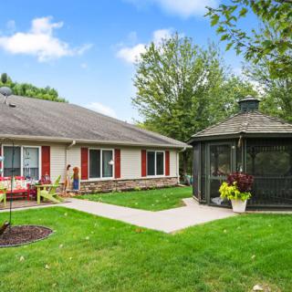 A quaint house with a well-maintained lawn and a charming gazebo in the backyard.