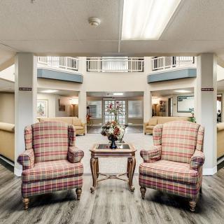 A modern lobby area featuring two plaid armchairs and a small wooden table under bright lighting.