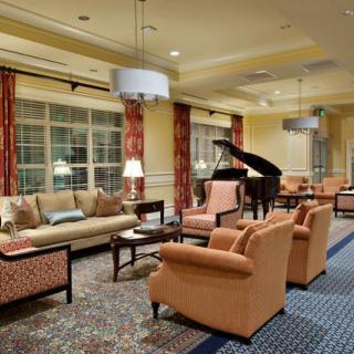 A cozy living room with sofas, armchairs, and a grand piano.