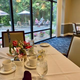 A elegantly set dining table near large windows with a view of an outdoor patio.