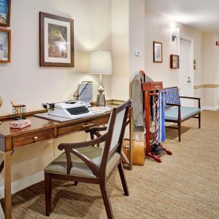 A well-organized office space with a desk and chairs in a hallway setting.