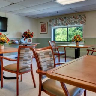 A well-lit dining area with tables and chairs, adorned with floral arrangements.