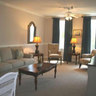 A cozy living room with a sofa, chairs, and wooden furniture illuminated by warm lamps.
