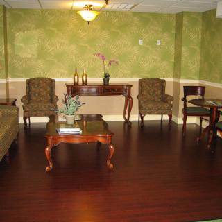 A cozy living room with green walls, featuring elegant furniture and hardwood flooring.