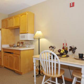 A cozy kitchenette with wooden cabinets, a microwave, and a small dining area.