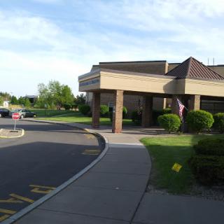A view of a building with a parking area surrounded by greenery.
