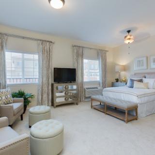 A serene and modern bedroom featuring soft colors, comfortable furniture, and plenty of natural light.