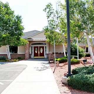 A well-maintained building entrance surrounded by trees and landscaping.