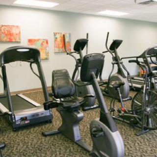 A gym room equipped with treadmills, stationary bikes, and elliptical machines.