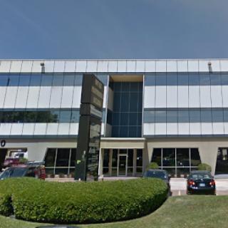 A modern commercial building featuring a sleek glass facade and well-maintained landscaping.