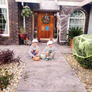 Two children dressed up for Halloween, sitting on the porch surrounded by festive decorations.
