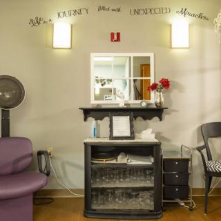 A cozy salon interior featuring a mirror, hair dryer, and decorative elements.