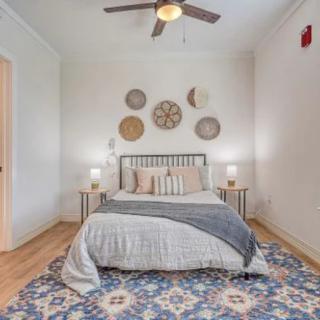 A cozy bedroom featuring a neatly made bed with decorative pillows, wall art above the headboard, and a patterned rug.