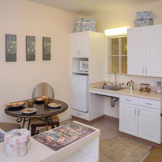 A cozy kitchen with a small dining table, white cabinets, and modern appliances.