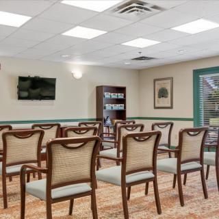 A neatly arranged conference room with chairs set up for a meeting, featuring a television and bookshelf.