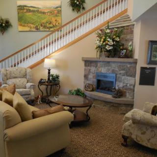 A cozy living room with a seating area, fireplace, and a staircase adorned with a decorative painting.