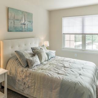 A cozy bedroom with a neatly made bed, soft pillows, and a calming painting on the wall.