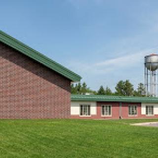 A modern building adjacent to a water tower, set in a lush green landscape.