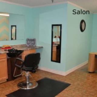 An interior view of a hair salon with a styling chair and mirror.