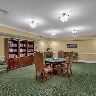 A quiet study room with bookshelves and a central table surrounded by chairs.