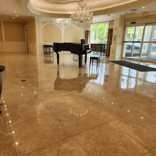 An elegant lobby featuring a grand piano, marble flooring, and a stunning chandelier.