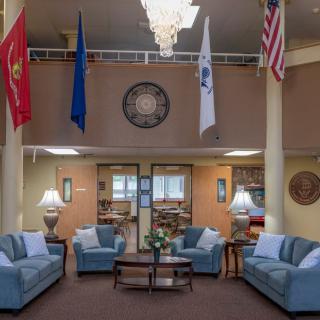 A spacious lobby featuring several sofas and a chandelier, with various flags displayed overhead.