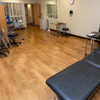 A clean and organized medical treatment area with chairs and a bed.