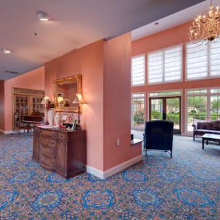 A spacious lobby with elegant furnishings, featuring a chandelier and large windows.