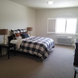 A well-furnished bedroom with a checkered bedspread and two bedside lamps.