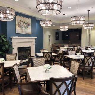 An elegant dining area with chandeliers and neatly arranged tables and chairs.