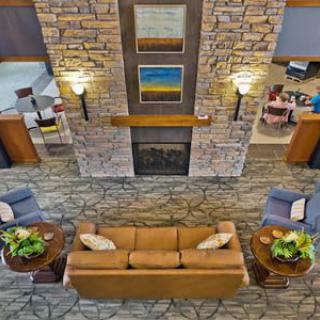A cozy and elegantly designed lobby featuring a central fireplace, surrounded by comfortable seating and tasteful decor.