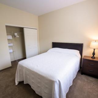A minimalist bedroom with a neatly made bed and a lamp on the nightstand.