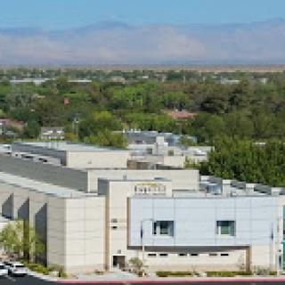 A modern institutional building surrounded by green landscapes and hills in the background.