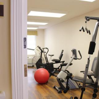 A small indoor gym featuring various exercise equipment including a stationary bike, treadmill, and an exercise ball.