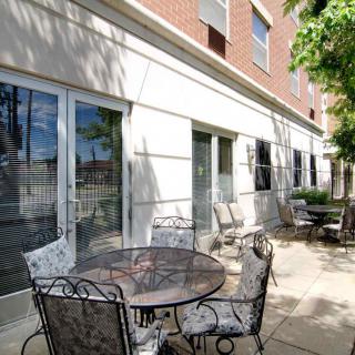 A sunny patio with wrought iron tables and chairs outside a building.