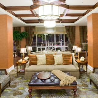 An elegantly decorated living room with a central sofa, surrounded by stylish furniture and warm lighting.