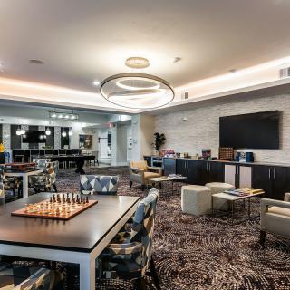 A modern lounge area with a chess board, comfortable seating, and a large television.